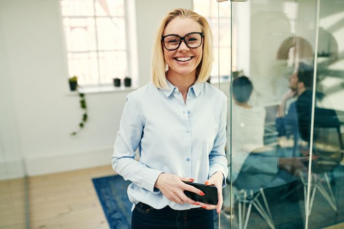 Portrait of blonde businesswoman smiling and holding a cell phone