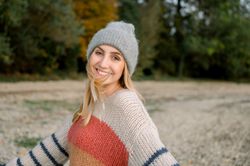 Happy woman with arms outstretched wearing knitwear and hat