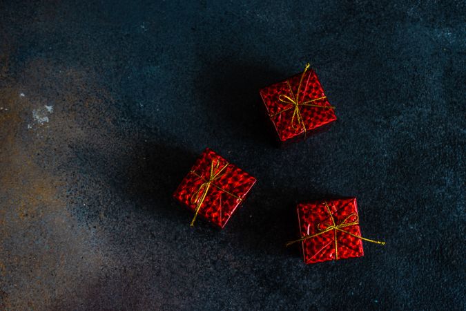 Three decorative red gift boxes on dark table