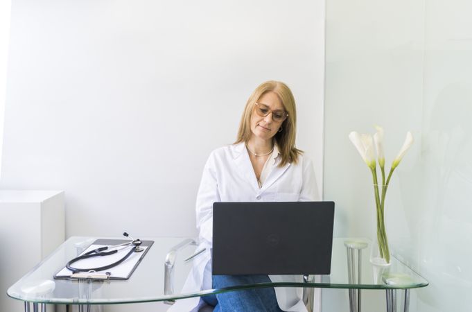 Female doctor working on laptop in medical office.