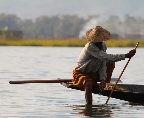 Man in brown hat kayaking in river