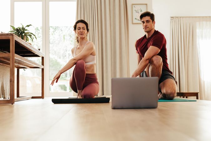 Couple stretching watching fitness video tutorial online on laptop
