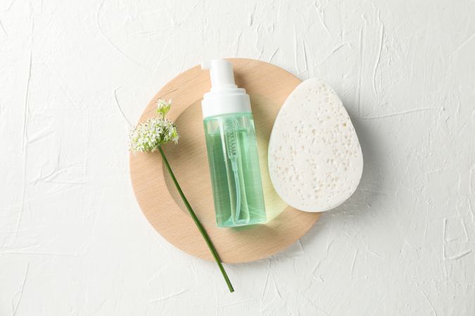 Lotion, allium flower and sponge on blank background, copy space