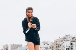 Content young woman in casual wear browsing smartphone at city street