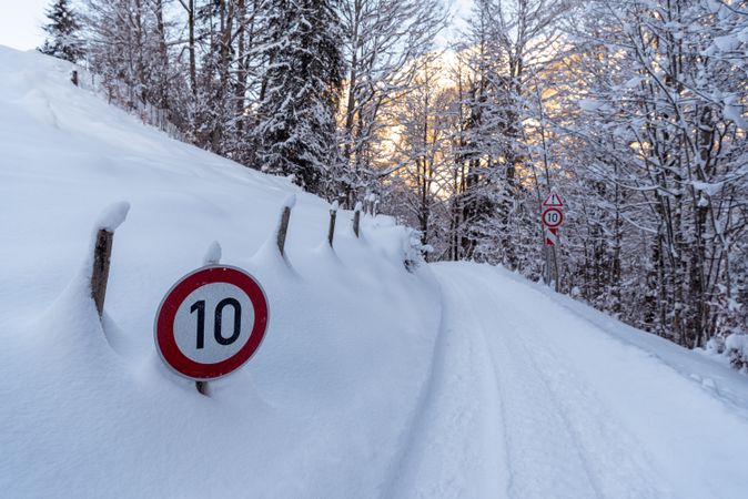 Snow-covered forest road and road sign in the Bavarian Alps, Germany