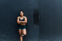 Hispanic sportswoman standing near wall