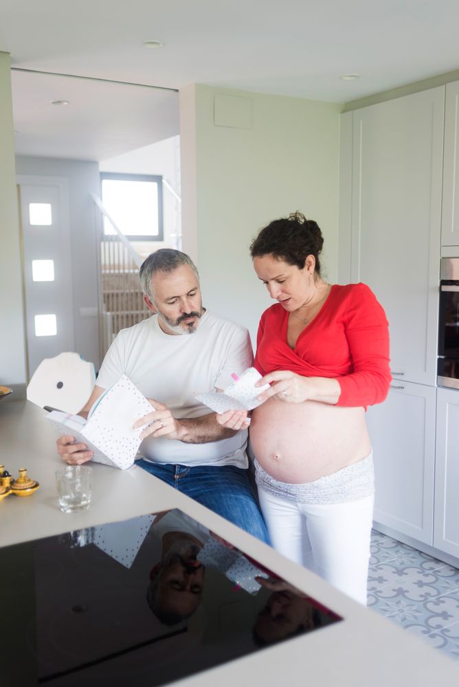 Couple looking through two recipe books in kitchen