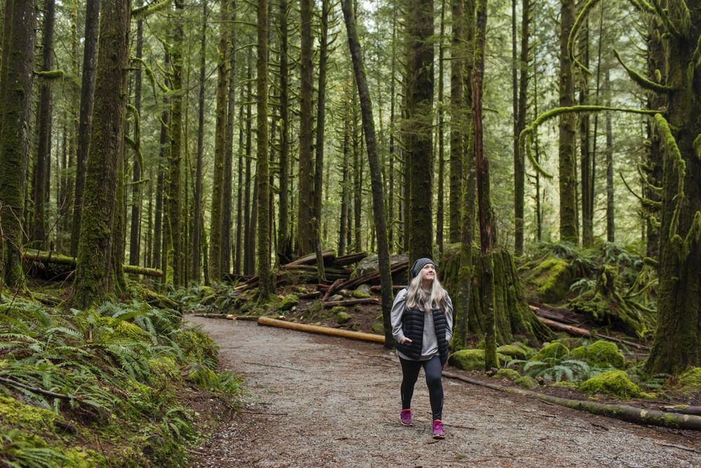 Woman with her hands in her pockets hiking in forest
