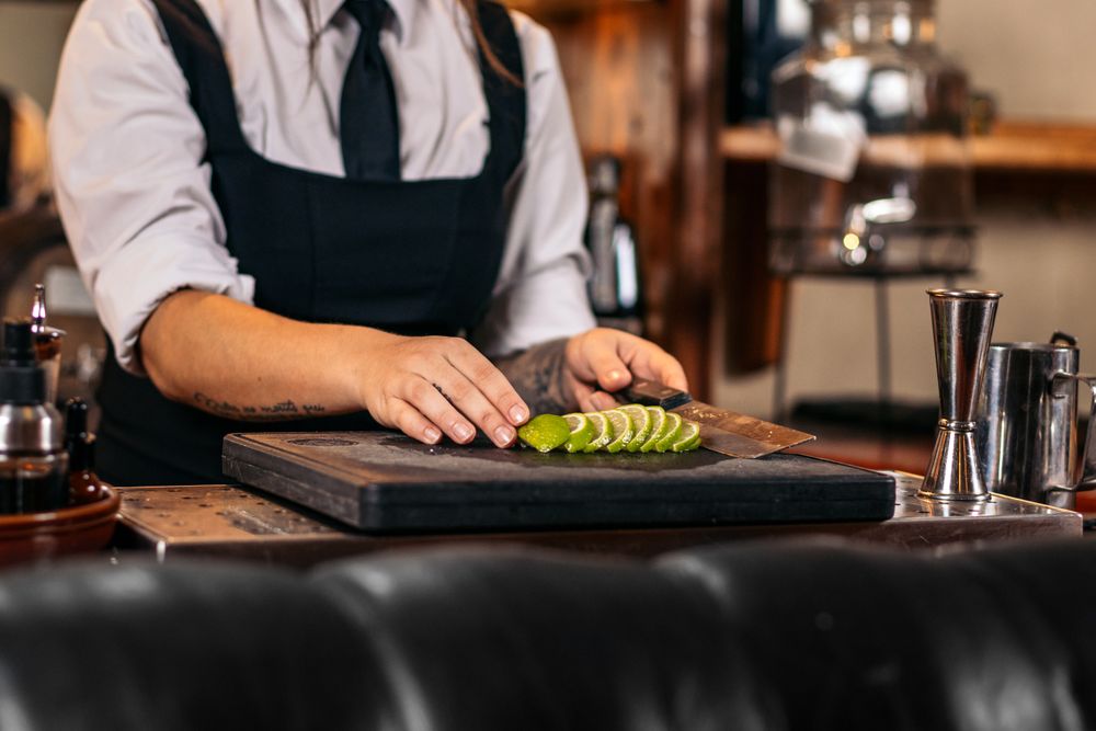 Close-up of a female bartender cutting limes to prepare cocktails