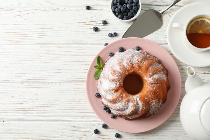 Cake with powder sugar and blueberry on wooden background, space for text