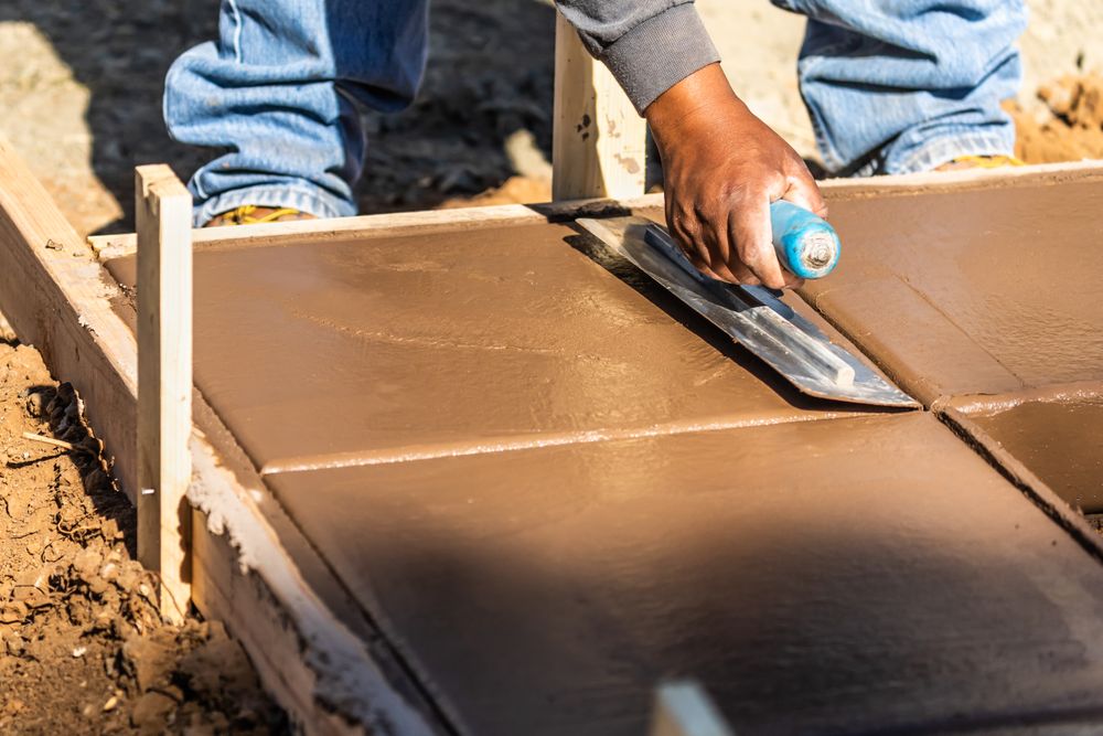 Construction Worker Using Trowel On Wet Cement Forming Coping Around New Pool