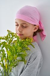 Kid in pink headband enjoying smell of wildflowers