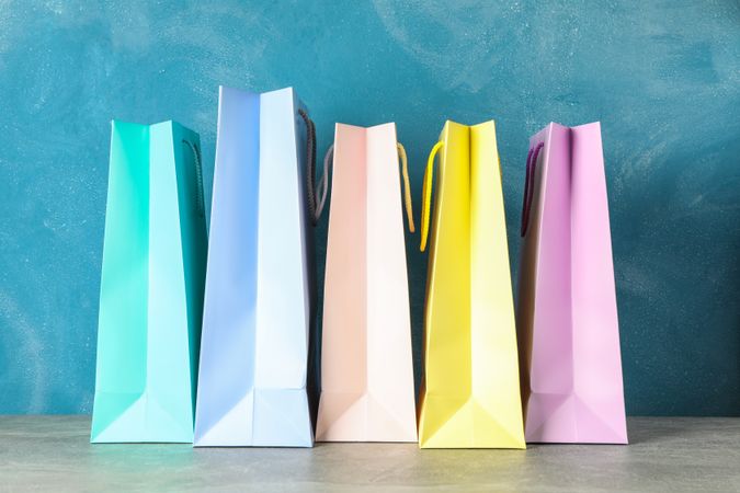 Color bags on grey table against blue background, copy space