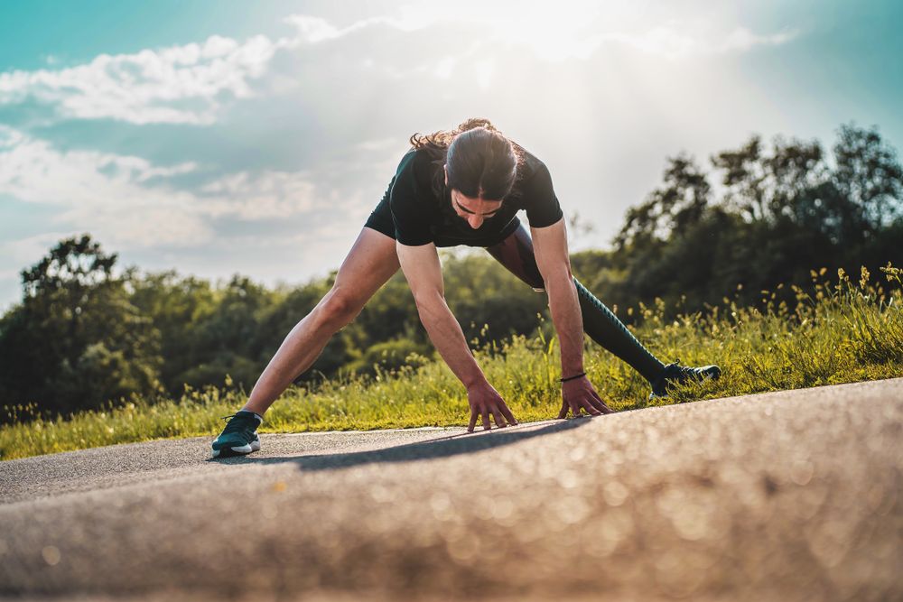 Young athlete with an artificial limb does stretching exercises in the park