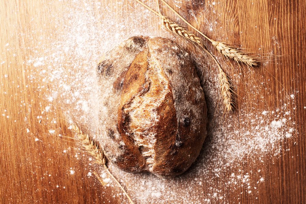 Top view of round loaf of bread with wheat chaff and flour