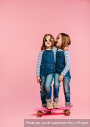Twin girls wearing fashion clothes with skateboard on pink background 47Vek5