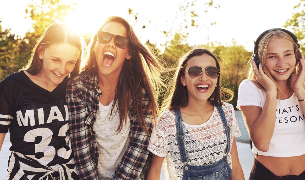 Group of female teenagers standing in a row and smiling in the sun