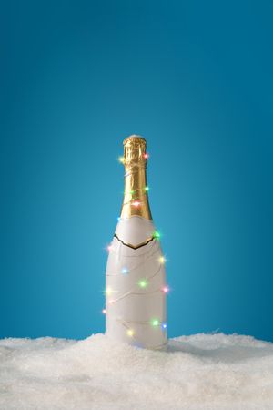 Champagne bottle with lights and snow on blue background