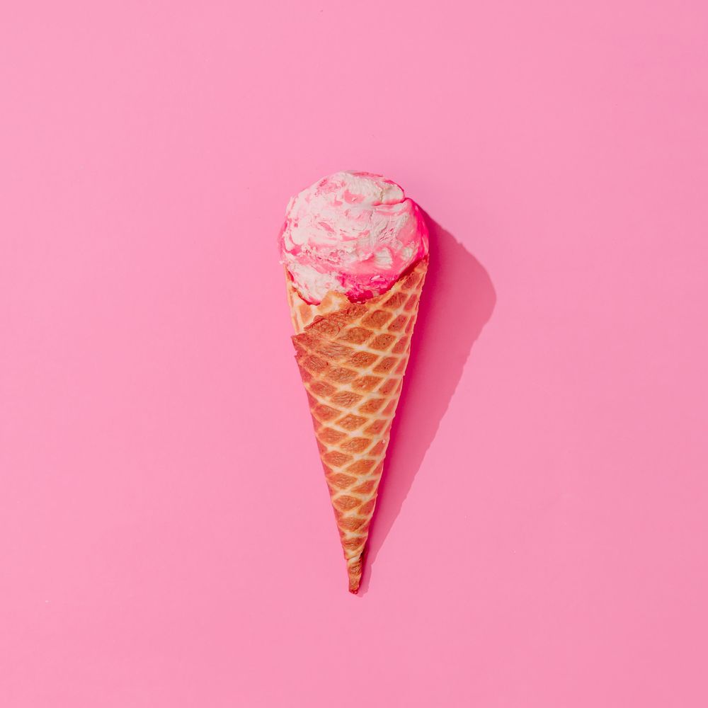 Waffle cone of pink ice cream on pink background