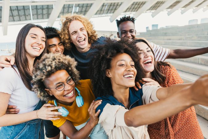 Group of young multicultural people taking selfie portrait with smart phone outdoors