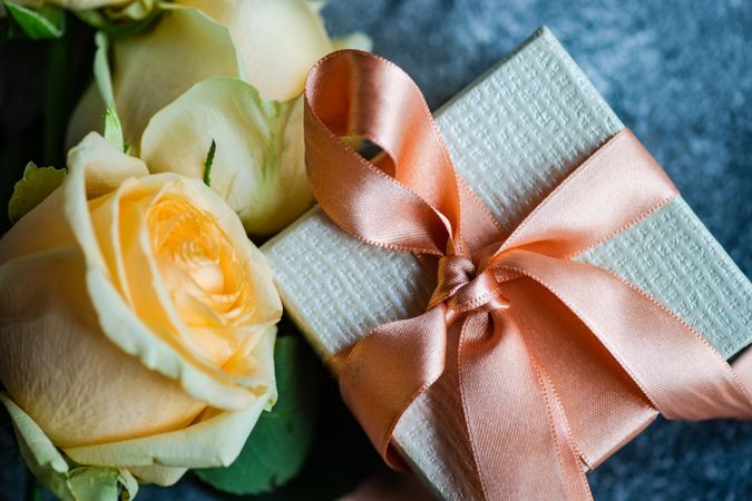 Top view of yellow flower on grey table with small giftbox