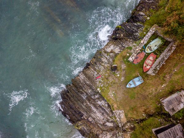 Boats on small part of seashore washing by foamy waves