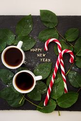 inscription of new year on a board with sprigs leaves and red candy