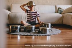 Boy playing music with cooking pots at home 4A7xq0