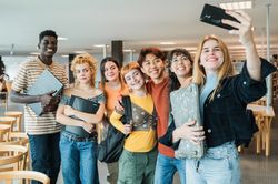 Multiracial classmates taking selfie in library