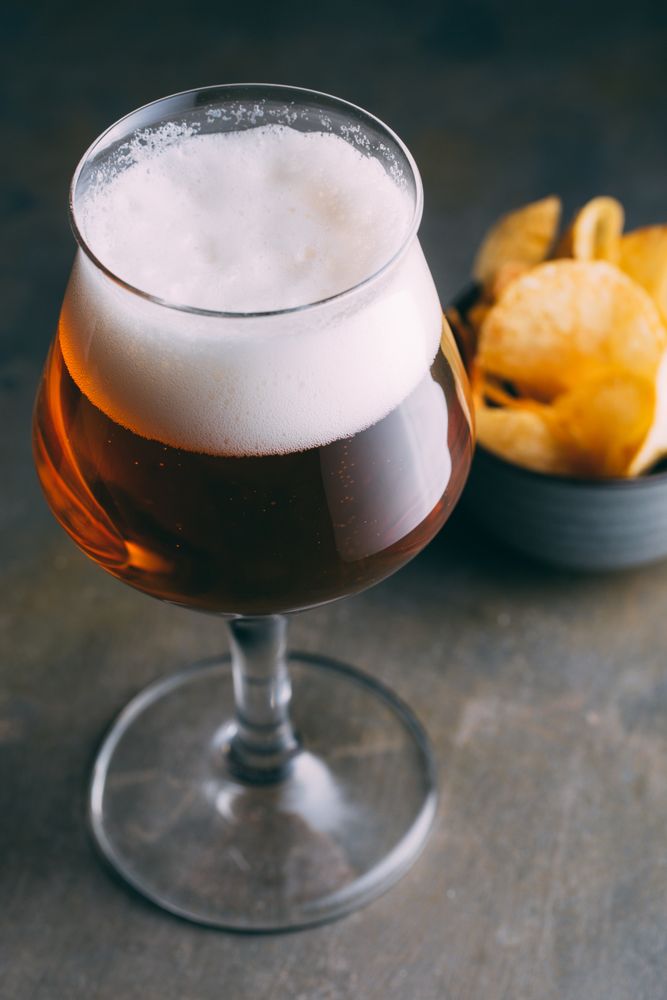 Glass of beer and chips on dark and grunge background