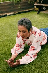 Woman laying on grass looking at mobile phone outside