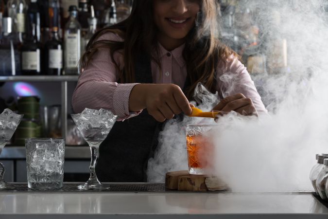 Bartender squeezing orange peel over a Negroni cocktail