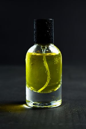 Yellow glass bottle with droplets in dark studio
