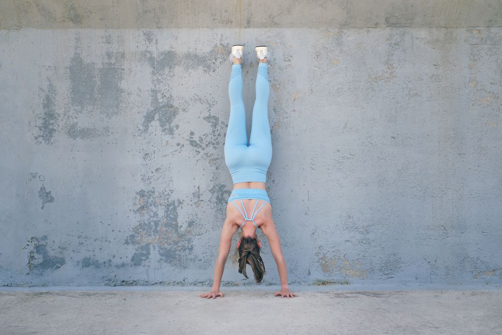 Anonymous athlete standing on hands against rough wall