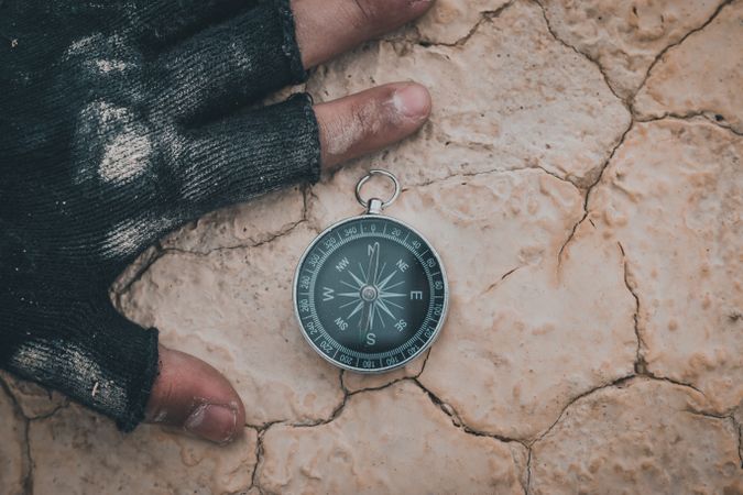 Compass near hand on dry desert area