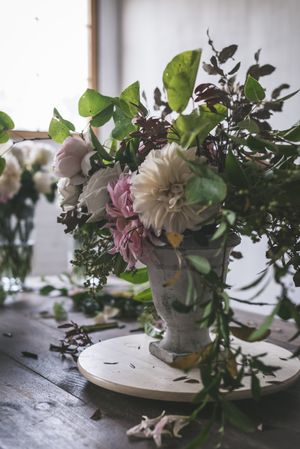 Composition of flowers and plants in vintage vase on board