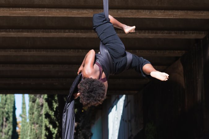 Healthy woman doing aerial yoga in city