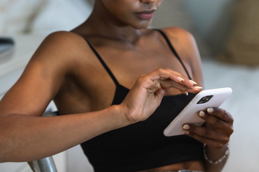 Anonymous Black woman using smartphone while sitting on chair