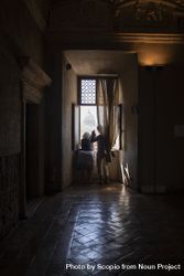Back view of two people standing at the window in a dark room 4dgZD5
