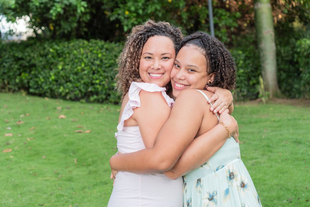 Young mother and teenage daughter hug and smile at the camera
