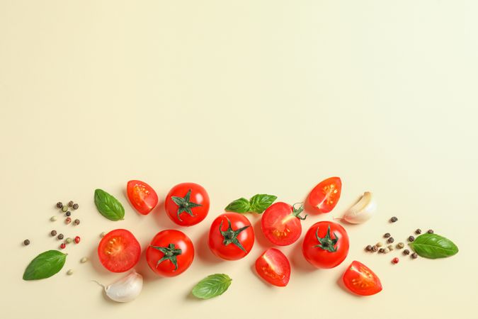 Flat lay composition with fresh cherry tomatoes, pepper, garlic and basil on color background, space for text. Ripe vegetables