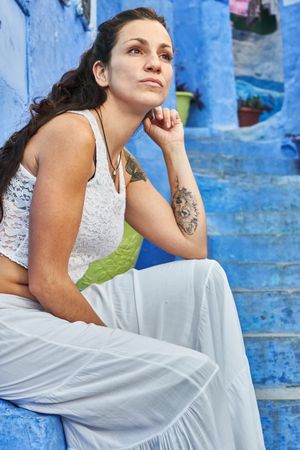 Pensive woman sitting on steps between ancient buildings