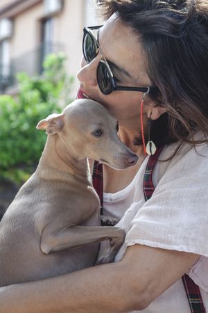 Woman kissing greyhound while relaxing on street