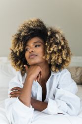 Black woman lying on bed in bedroom