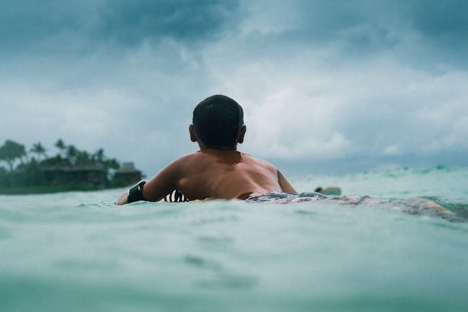 Body of male surfer floating on water on Hawaiian beach