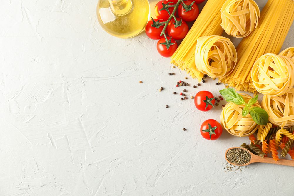 Composition with pasta, tomatoes, spices and olive oil on bright background, space for text
