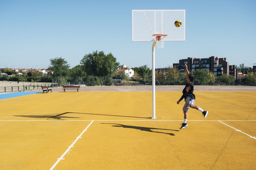 Young man playing on basketball court outdoor.