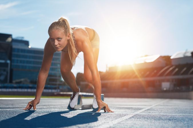 Professional female track athlete in set position on sprinting blocks