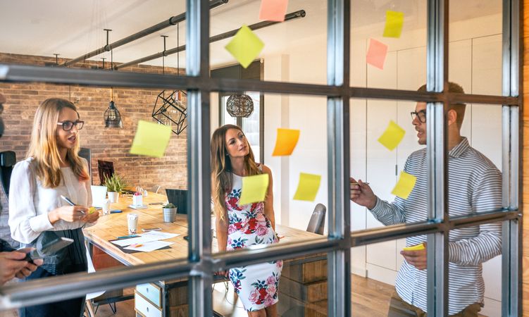 Business people in a work meeting placing sticky notes on the wall