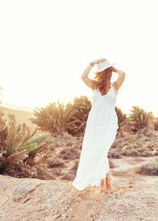 Woman in white dress in dry field in sunlight